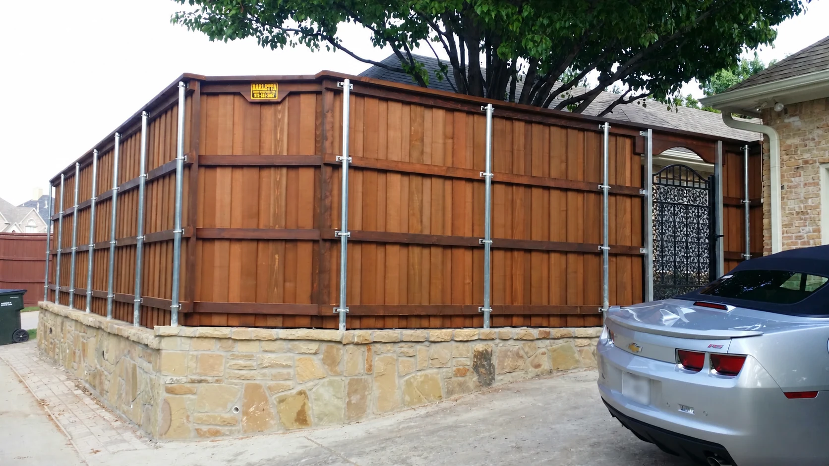 Cedar fence over a stone wall with a metal gate