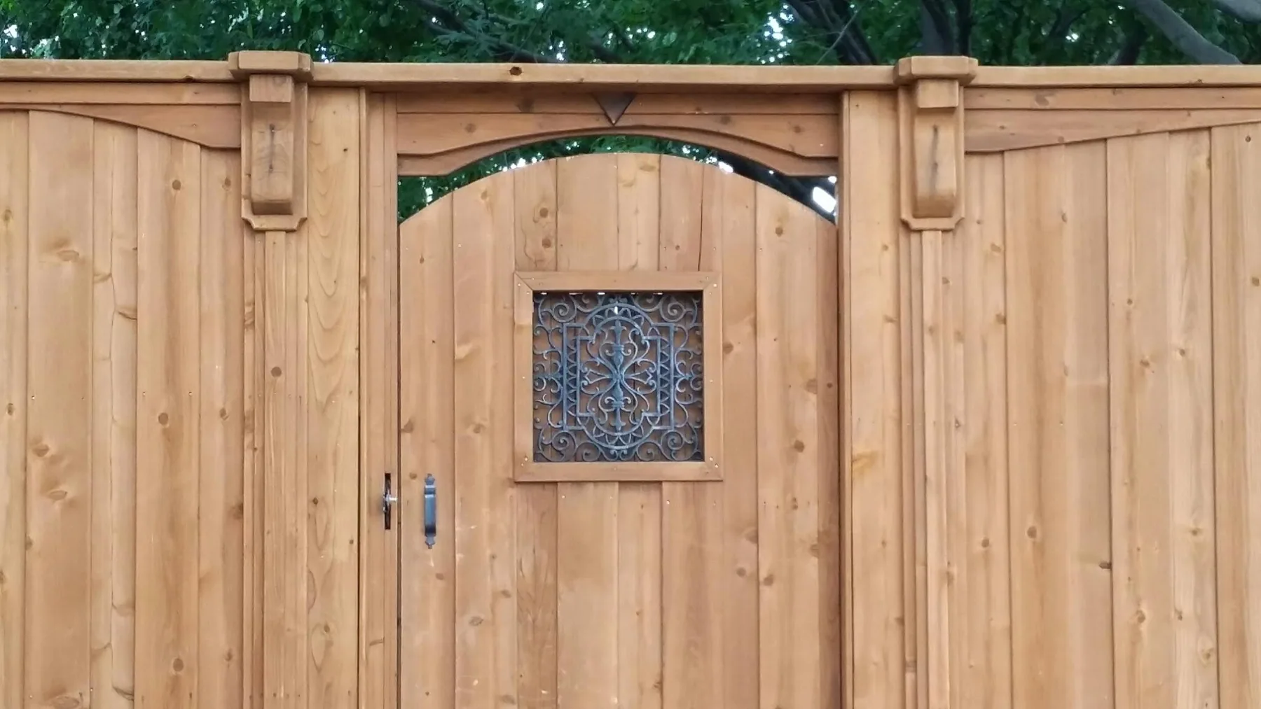 Arched cedar gate with a decorative metal inset