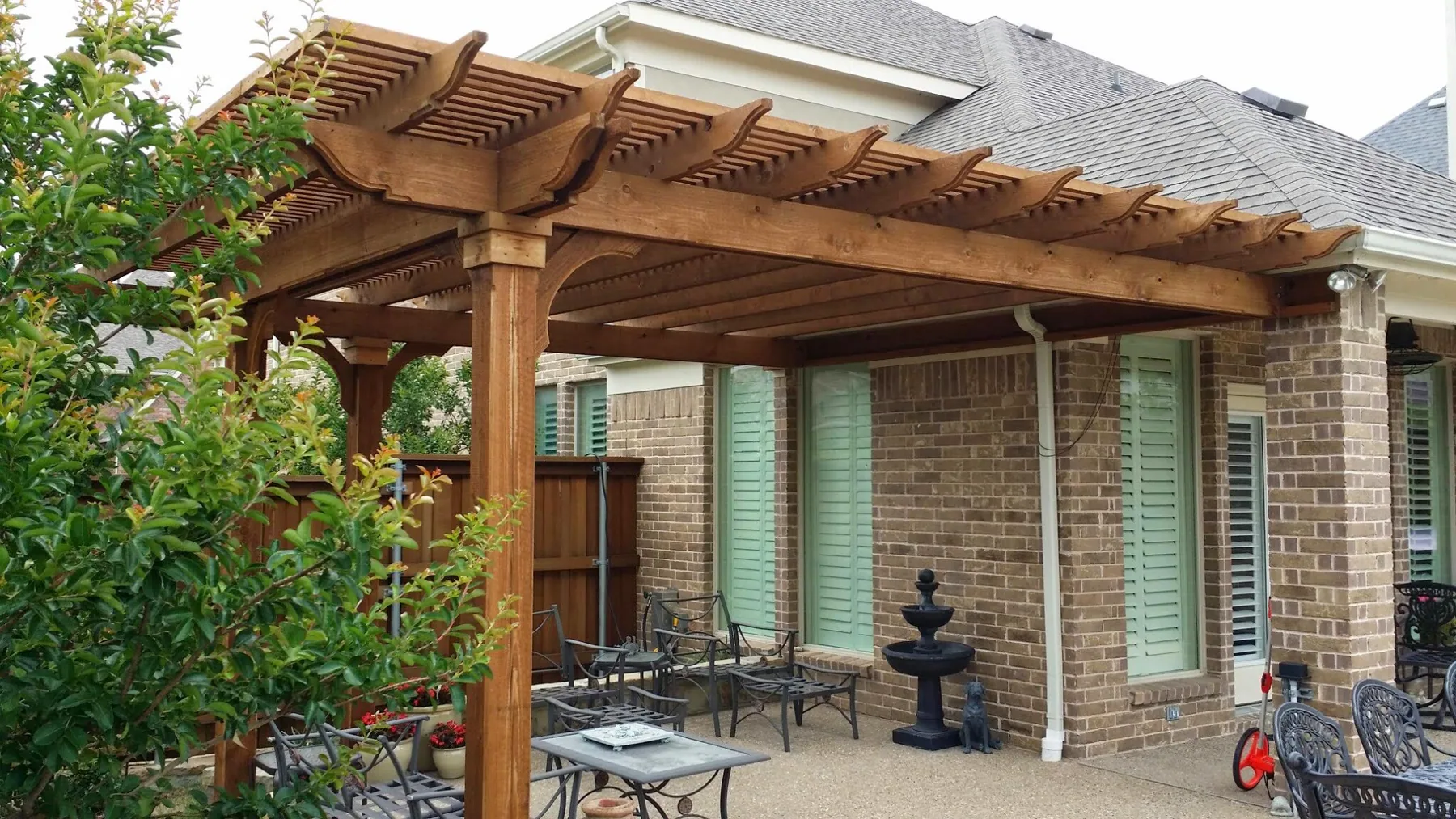 Wood pergola extending over a backyard patio