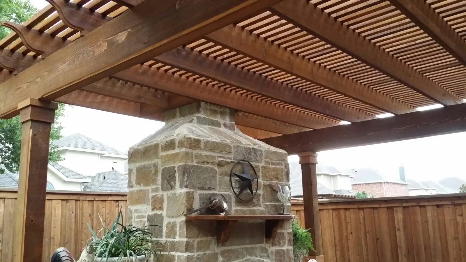 Wood pergola above a stone outdoor feature